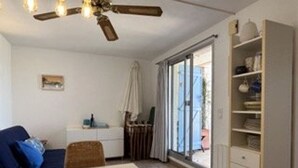 A room with a dining table, chairs, a ceiling fan, a window with curtains, and a built-in shelving unit. - 2-room apartment with terrace and parking in Banyuls-sur-Mer (Banyuls-sur-Mer)