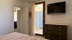 A bedroom with a bed, a dresser, and a TV mounted on the wall. - 2-room apartment with terrace and parking in Banyuls-sur-Mer (Banyuls-sur-Mer)