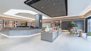 A modern lobby with a central reception desk, seating area, and bookshelves.