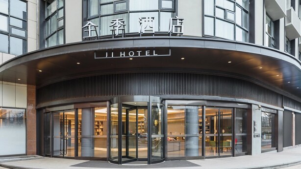 A hotel entrance with a revolving door, glass facade, and signage in both Chinese and English.