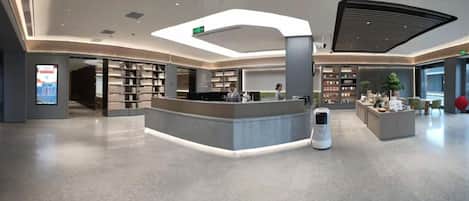 A modern lobby with a reception desk, a self-service kiosk, and a large digital display.