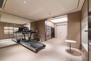 Una habitación de hotel moderna con una cinta de correr, una mesita y una lavadora.