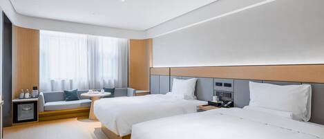 A hotel room with two beds, a sofa, a small table, and a window with curtains.
