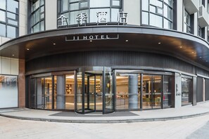 A hotel entrance with a revolving door, glass facade, and signage in both Chinese and English.
