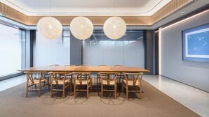 A modern conference room with a long table, six chairs, and three spherical pendant lights.