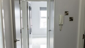 Un pasillo con puertas blancas, un teléfono y una ventana.