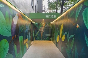 A corridor with a mural of birds and leaves, leading to a door with a sign above it. - Hi Inn (Shanghai Lujiabang Road Metro Station) (Shanghai)
