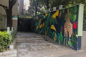 Eine Treppe führt zu einem Gebäude, dessen Wand mit einer Giraffen- und Pflanzenwandmalerei versehen ist.