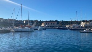 A marina with several sailboats docked, surrounded by buildings and hills. - Beachfront Apartment with Terrace & Wi-Fi in Lumio, 4 Guests (Lumio)