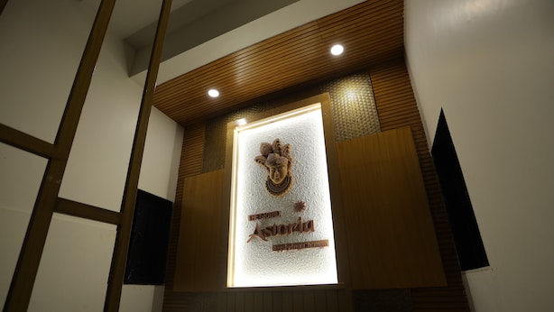 A reception area with a wooden ceiling, a glass display case, and a plaque with text. - The Grand Astoria Somnath (Veraval)