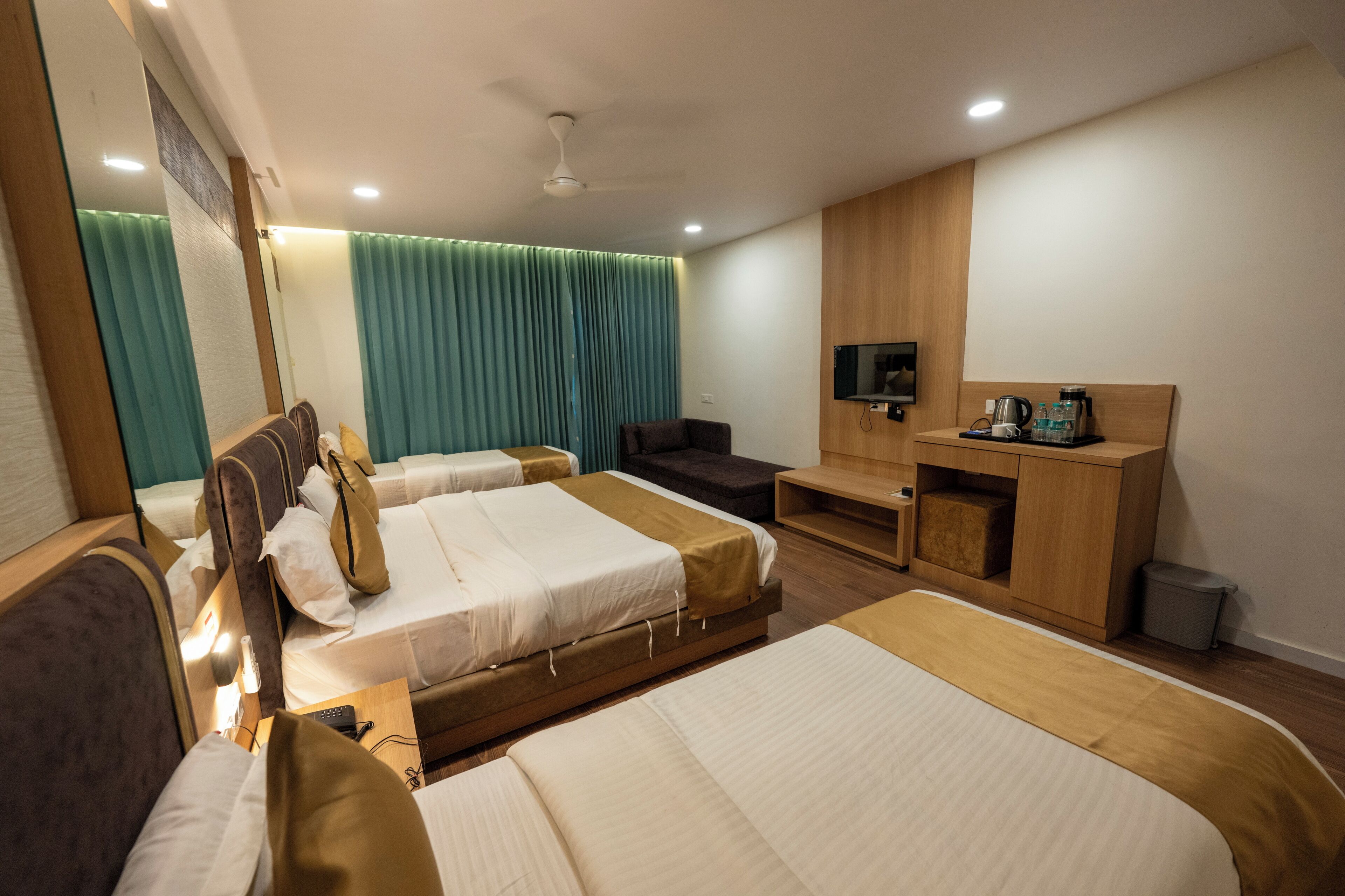 A hotel room with two beds, a TV, a desk, and a mirror.