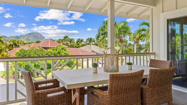 A covered outdoor seating area with wicker furniture, a table, and a woven basket.