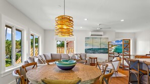 A spacious dining area with a round wooden table, multiple chairs, and a large bowl centerpiece.