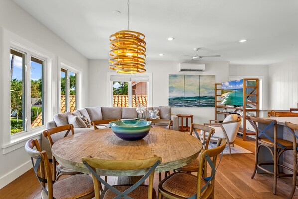 A spacious dining area with a round wooden table, multiple chairs, and a large bowl centerpiece.