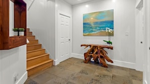 A staircase leading to a landing with a wooden table and a painting of a beach scene.