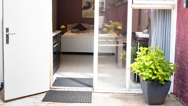 A modern bedroom with a bed, bedside table, lamp, and a window with curtains. - Studio (Soesterberg)