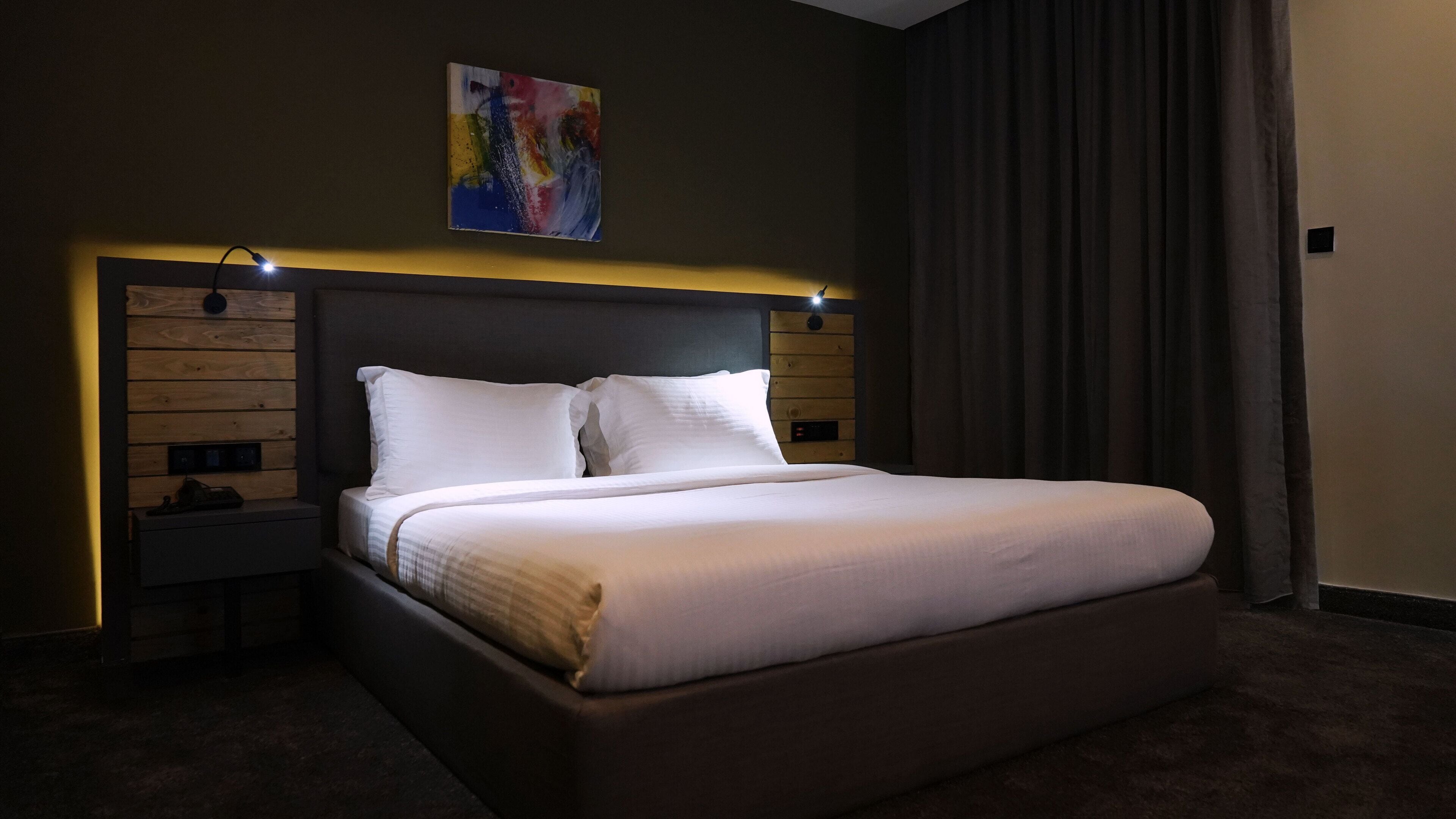 Una cama bien hecha con ropa de cama blanca en una habitación de hotel.