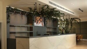 A reception desk with a marble top, shelves, and a photo backdrop. - Aitch Boutique Hotel - an LIH Hotel (Madaba)