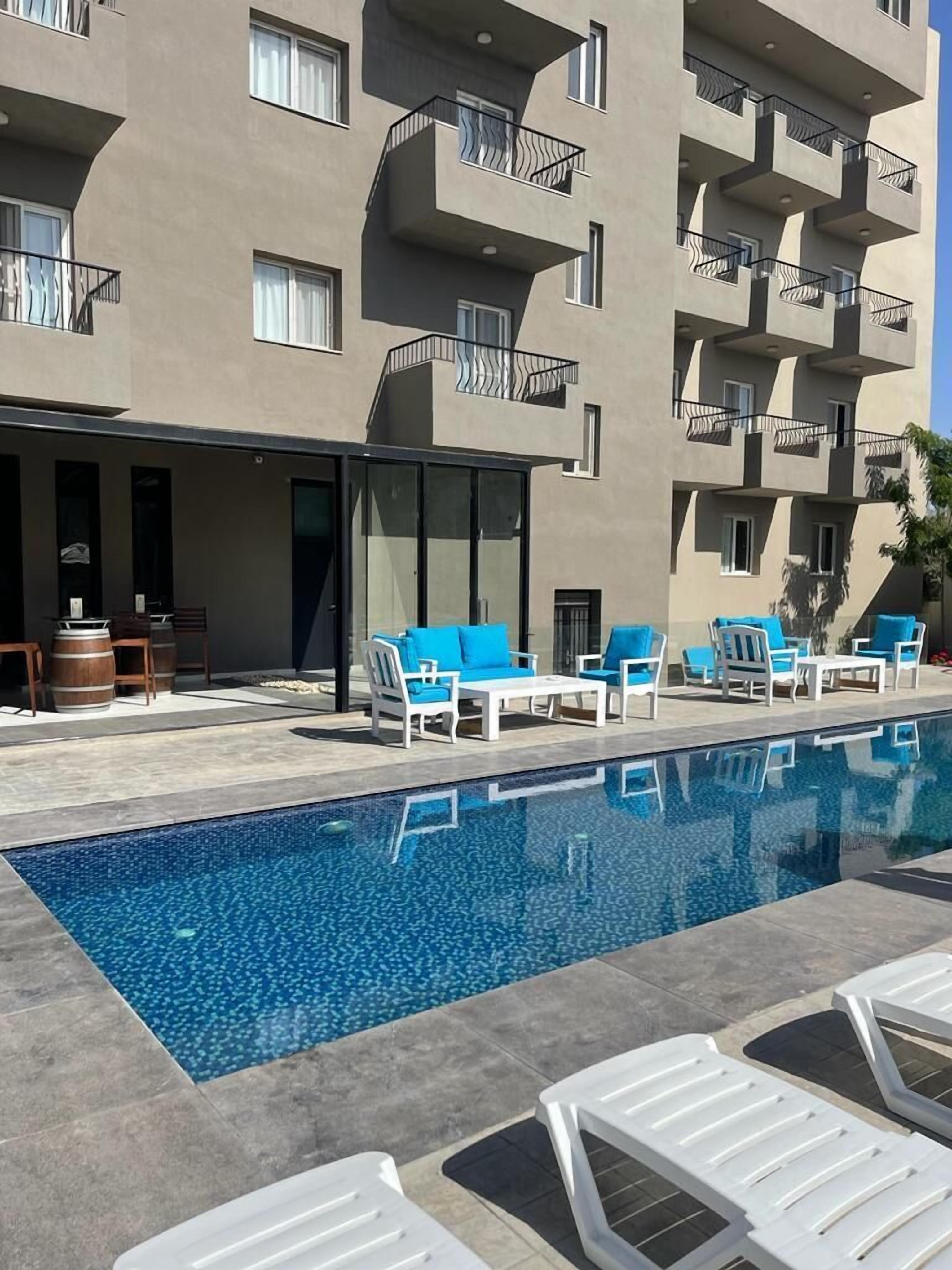 Un hotel moderno con piscina, mobiliario exterior y un diseño arquitectónico único.