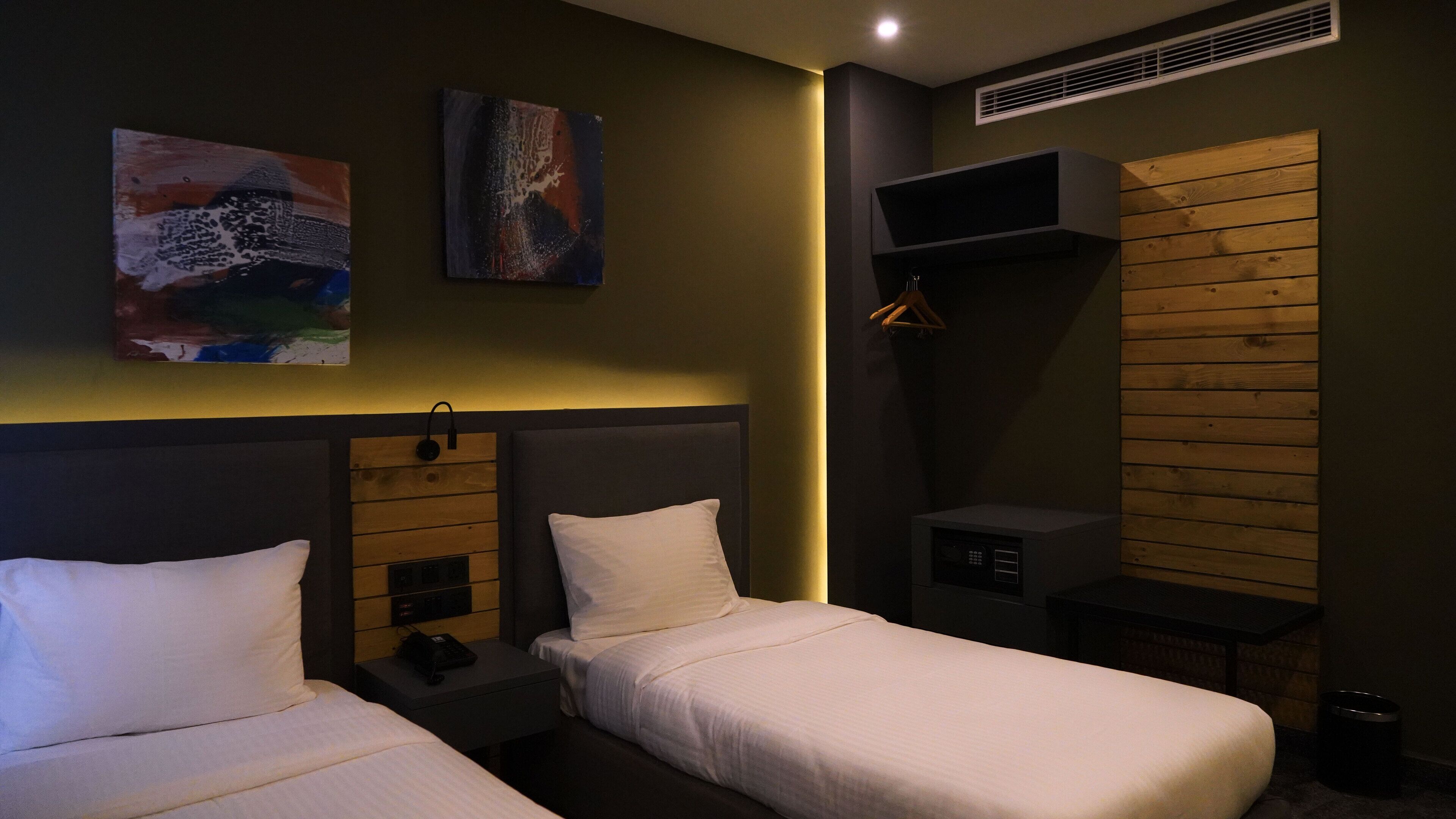Ein Hotelzimmer mit zwei Betten, einer Holzwandverkleidung, einem kleinen Tisch und einem fest montierten Heizkörper.