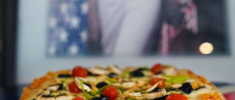 A pizza with various toppings in front of a framed picture.