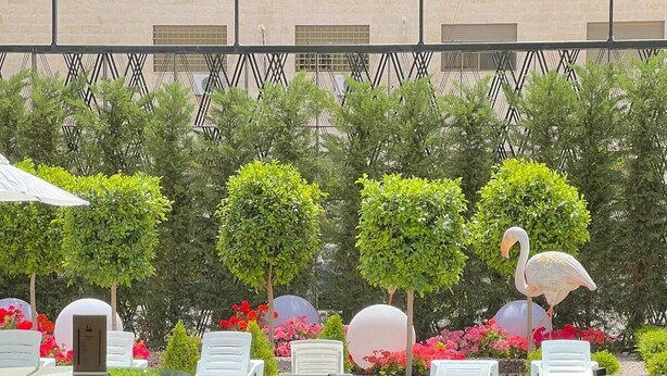 An outdoor seating area with tables and chairs, a pool, and decorative flamingos. - Aitch Boutique Hotel - an LIH Hotel (Madaba)