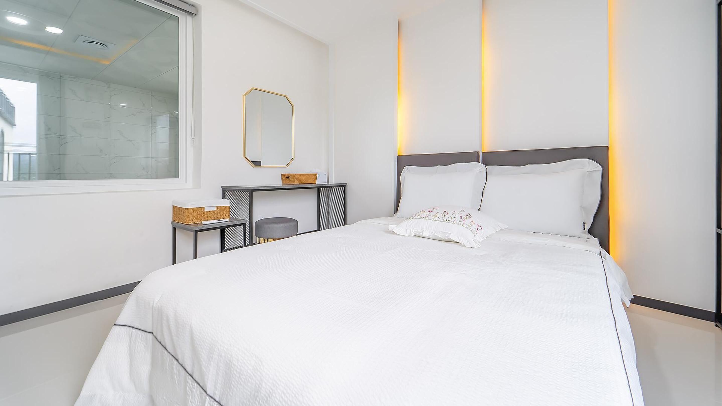 Une chambre à coucher moderne avec un grand lit, une table de chevet, un miroir et une fenêtre.