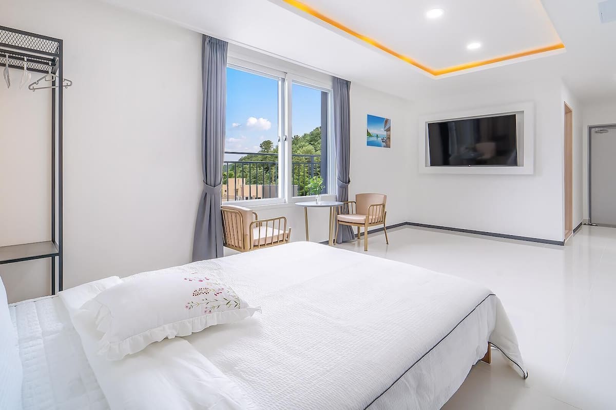 Une chambre d’hôtel moderne avec un grand lit, une télévision, un balcon avec vue et une porte.