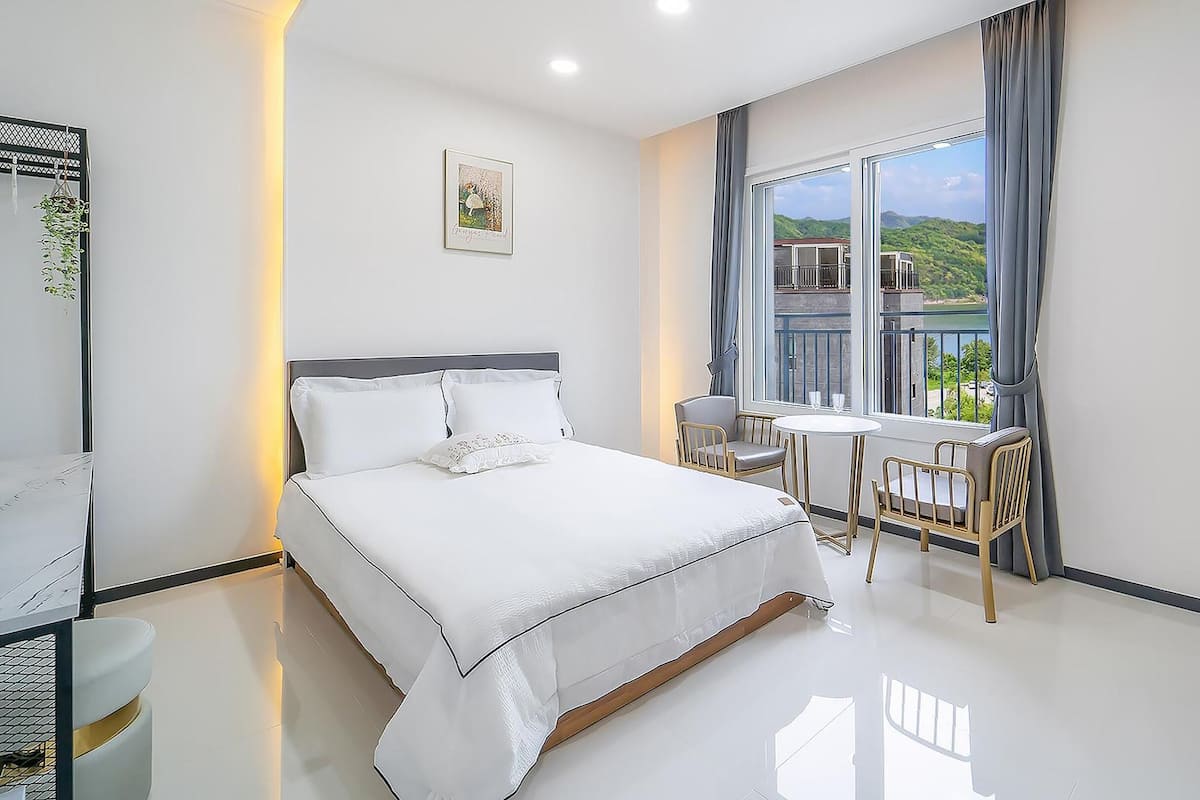 Une chambre d’hôtel moderne dotée d’un grand lit, d’un balcon avec une table et des chaises, et offrant une vue panoramique.
