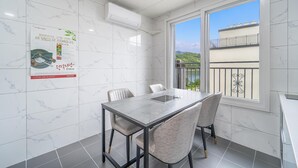 Een moderne keuken met een marmeren achterwand, een eettafel met stoelen en een raam met uitzicht op een balkon.