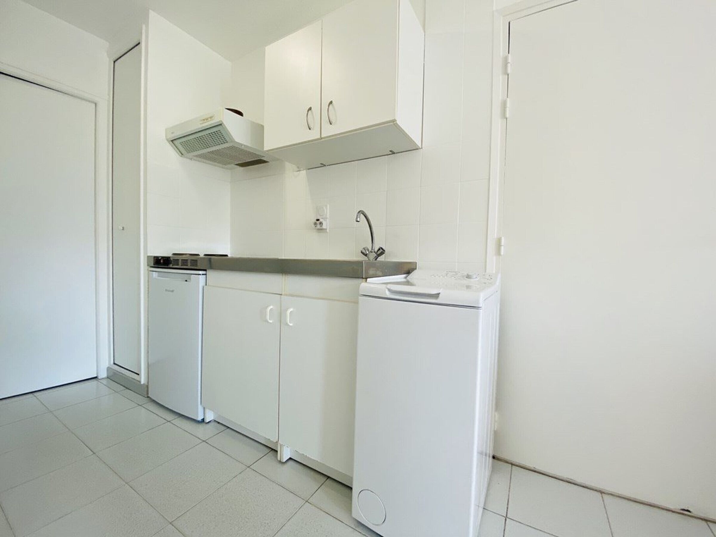 A compact kitchen with white cabinets, a built-in dishwasher, and a sink.