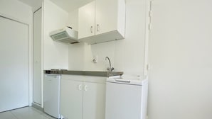 A compact kitchen with white cabinets, a built-in dishwasher, and a sink. - Cozy 1-Bedroom Apartment with Terrace, 100m from Beach, Parking Included - Calvi (Calvi)