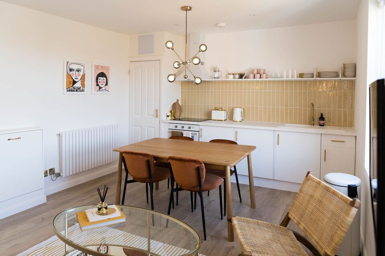 Een moderne keuken met witte kasten, een houten eettafel en een glazen salontafel.
