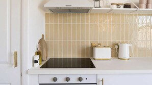 Una cocina con estufa blanca, encimera negra y salpicadero de azulejos.