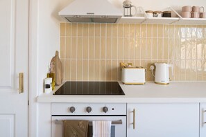 A kitchen with a stove, oven, and a countertop with a toaster and a kettle.