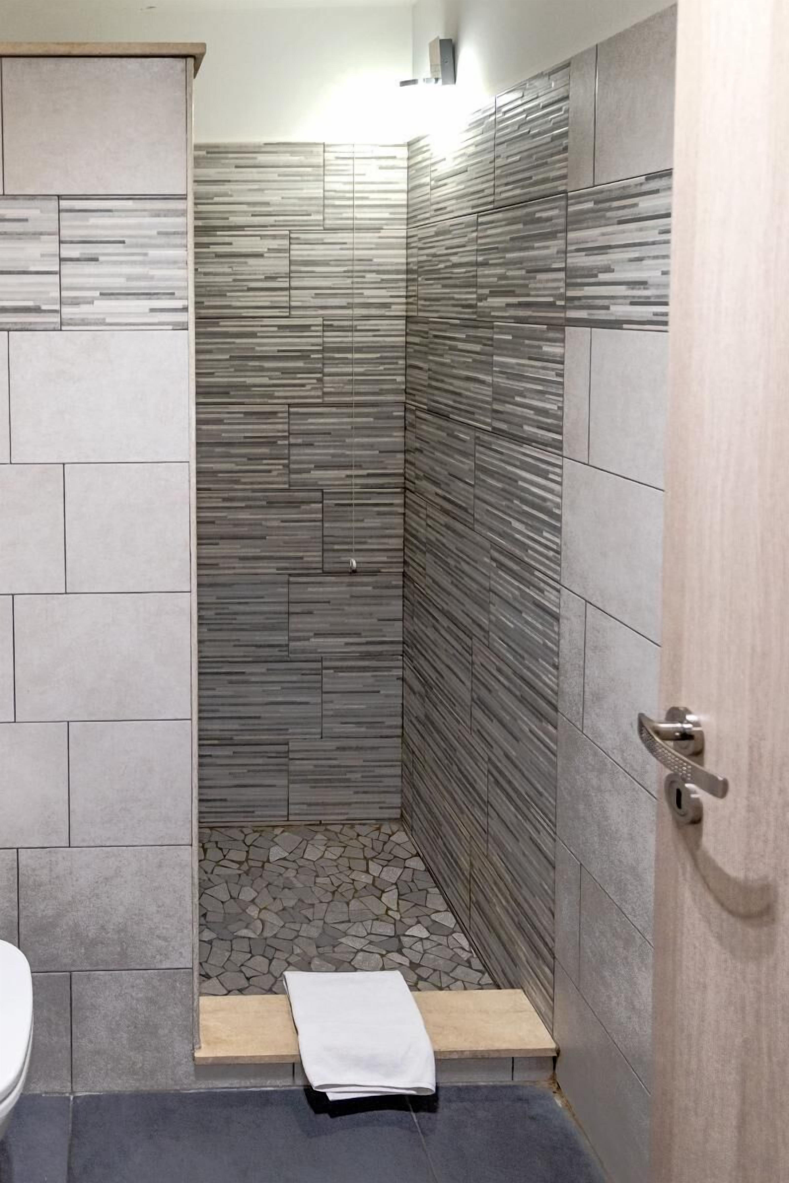 A modern bathroom with a shower area, tiled walls, and a wooden door.