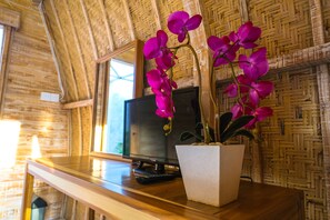 Mesa de madeira com uma orquídea em vaso e um controle remoto.