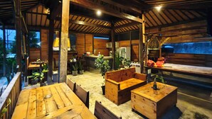 A rustic wooden interior with a dining area, wooden benches, and a bar. - Puri Sadewa Balangan (Jimbaran)