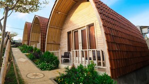 A modern, curved-roofed building with a covered porch and a garden area. - Puri Sadewa Balangan (Jimbaran)