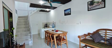 Un interior moderno con comedor, sofá, escalera y cocina.
