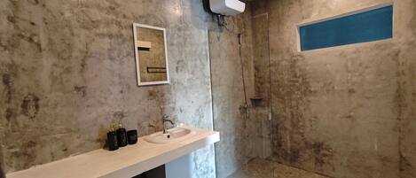 A bathroom with a white sink, mirror, and a shower area.