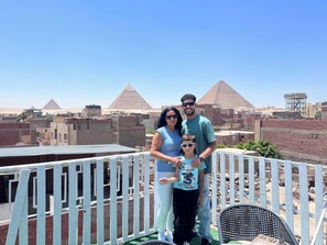 Une famille se trouve sur un toit, avec des pyramides en arrière-plan.