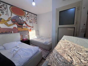 Un dormitorio con dos camas, un mural en la pared, un armario y una puerta.