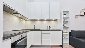 A modern kitchen with white cabinets, a built-in oven, and a countertop. - Comfortable Apartment in the Center | Close to Market Square and Railway Station (Wroclaw)