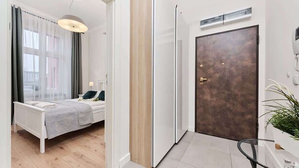 A modern hotel room with a bed, bedside table, and a view through a window with sheer curtains. - Comfortable Apartment in the Center | Close to Market Square and Railway Station (Wroclaw)