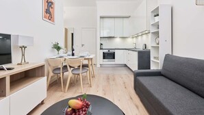 A modern apartment with a dining area, kitchenette, and a grey sofa. - Comfortable Apartment in the Center | Close to Market Square and Railway Station (Wroclaw)