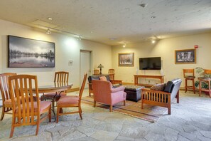 A living room with a stone floor, wooden furniture, a painting, a television, and a fireplace.