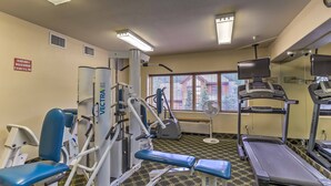 Een sportschool met trainingsapparatuur, een loopband en een raam met jaloezieën.