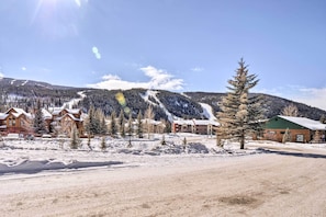 A snow-covered landscape with buildings, including a lodge with a green roof and a wooden cabin.