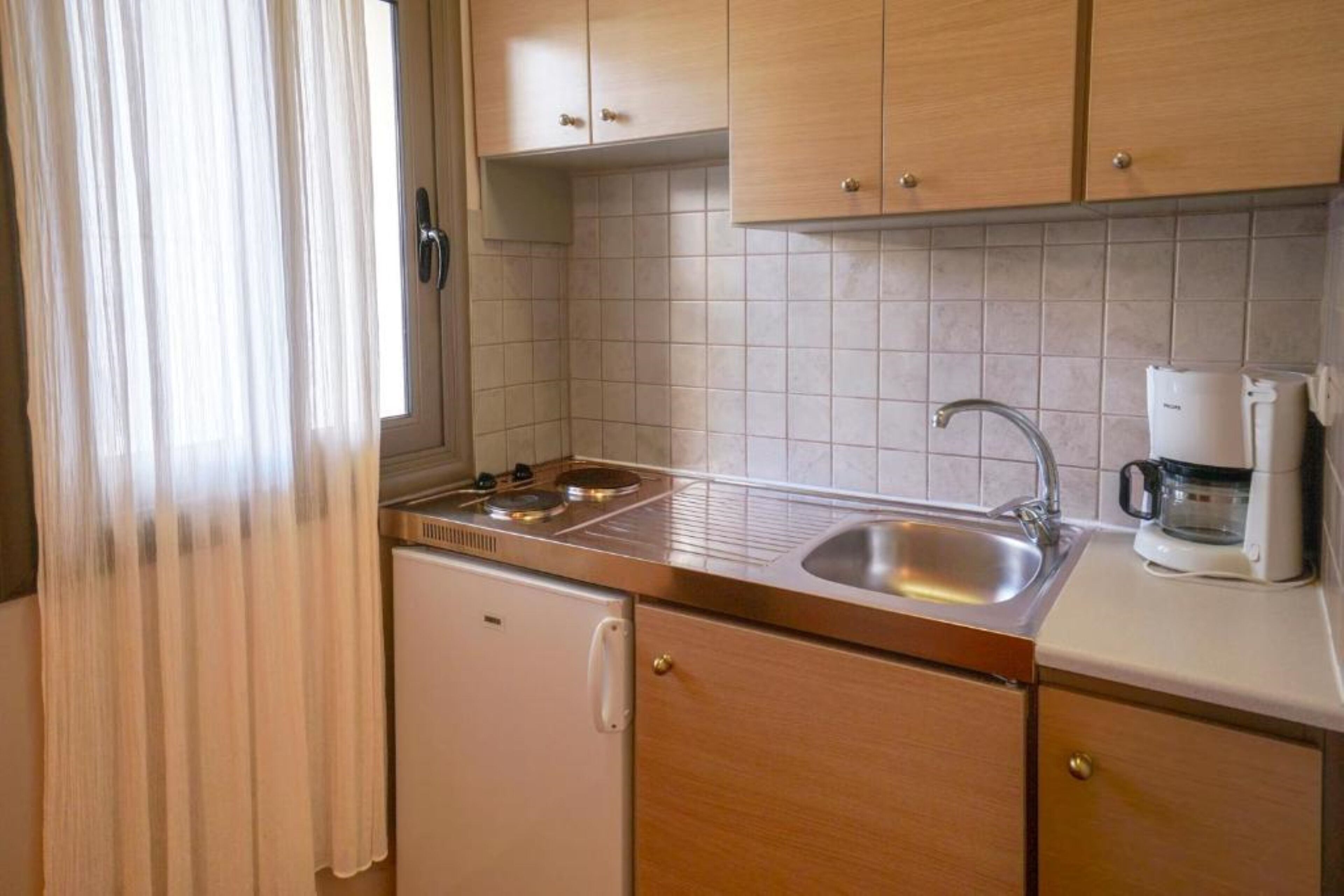 A compact kitchen with a sink, stove, and a coffee maker.
